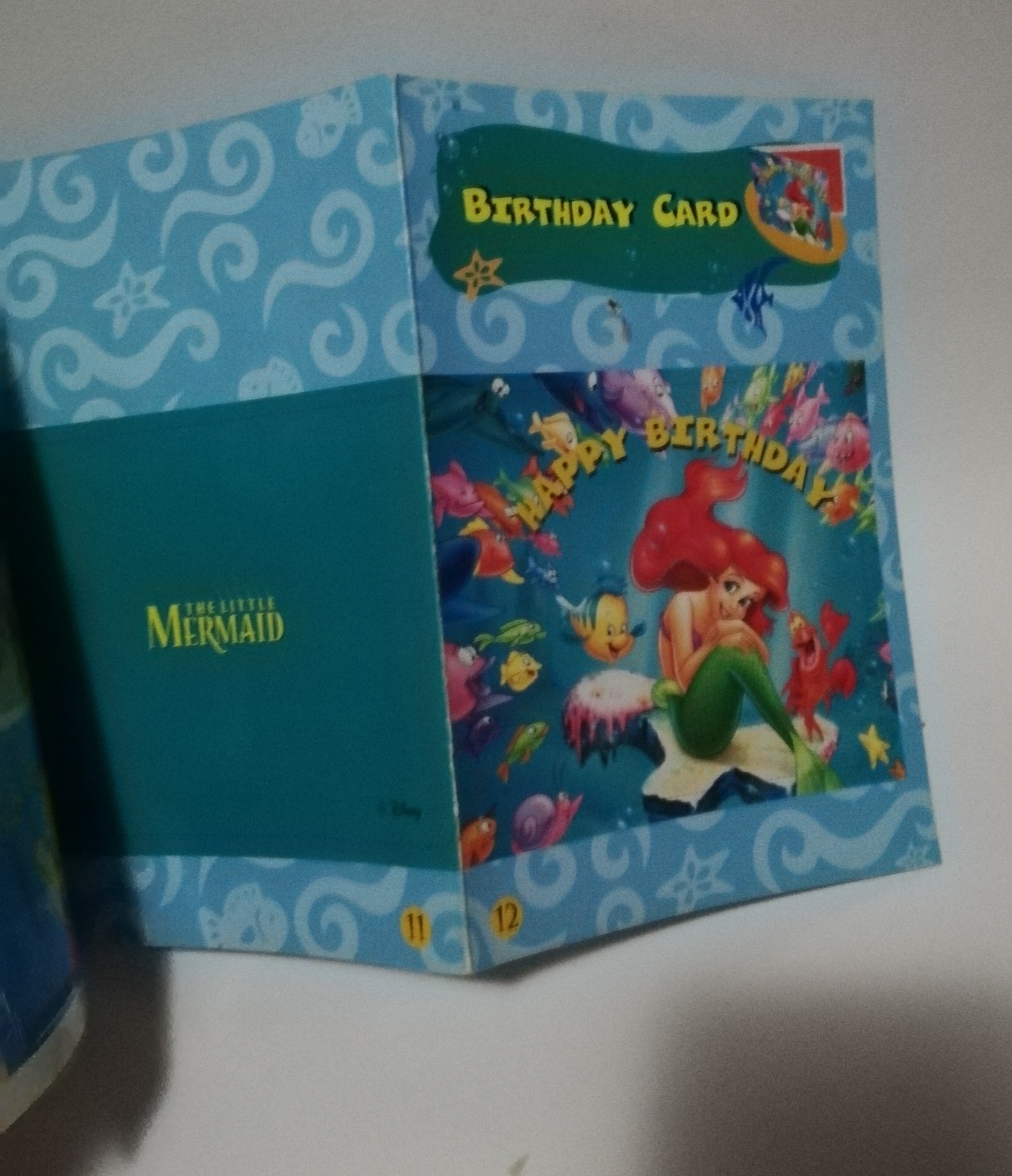 มีหลายภาพ, มีตำหนิ โปรดดูทุกภาพ, สมุดภาพเจ้าหญิงเงือกน้อยแอเรียล, the Little Mermaid ขนาด 19 cm, เป็นสมุดภาพการ์ด ที่คั่นหนังสือ ป้ายสมุดโทรศัพท์การ์ดอวยพรวันเกิดตัวแขวนโทรศัพท์มือถือเป็นกระดาษสแตนดี้และภาพระบายสี เป็นภาพเงือกน้อยแอเรียล Little Mermaid