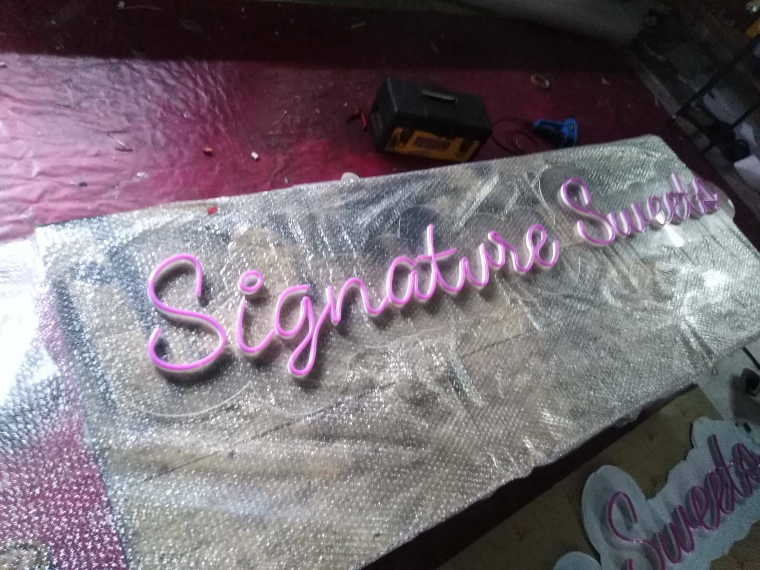 ป้ายไฟนีออนดัด วางบนอะคริลิค แสงสีชมพู - Signature sweets