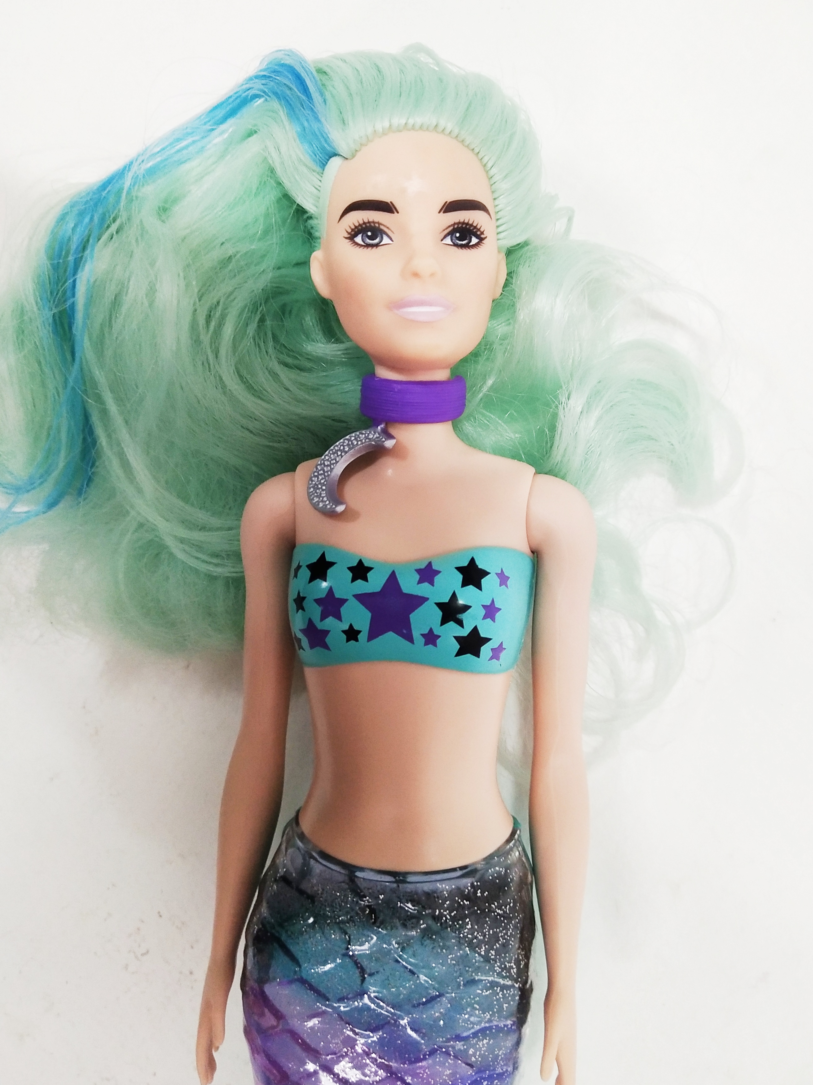 ตุ๊กตาบาร์บี้นางเงือกเปลี่ยนสี รุ่น Mattel Barbie Color Reveal Mermaid, สามารถเปลี่ยนหางกับหางของตัวอื่นๆใน Collection เดียวกันได้, บริเวณหน้าผากและเหลือคิ้วและสันจมูกเมื่อโดนน้ำเย็นจะเป็นลายตามภาพ , บริเวณผมตรงสีเข้มเมื่อโดนน้ำเย็นจะกลายเป็นสีม่วง