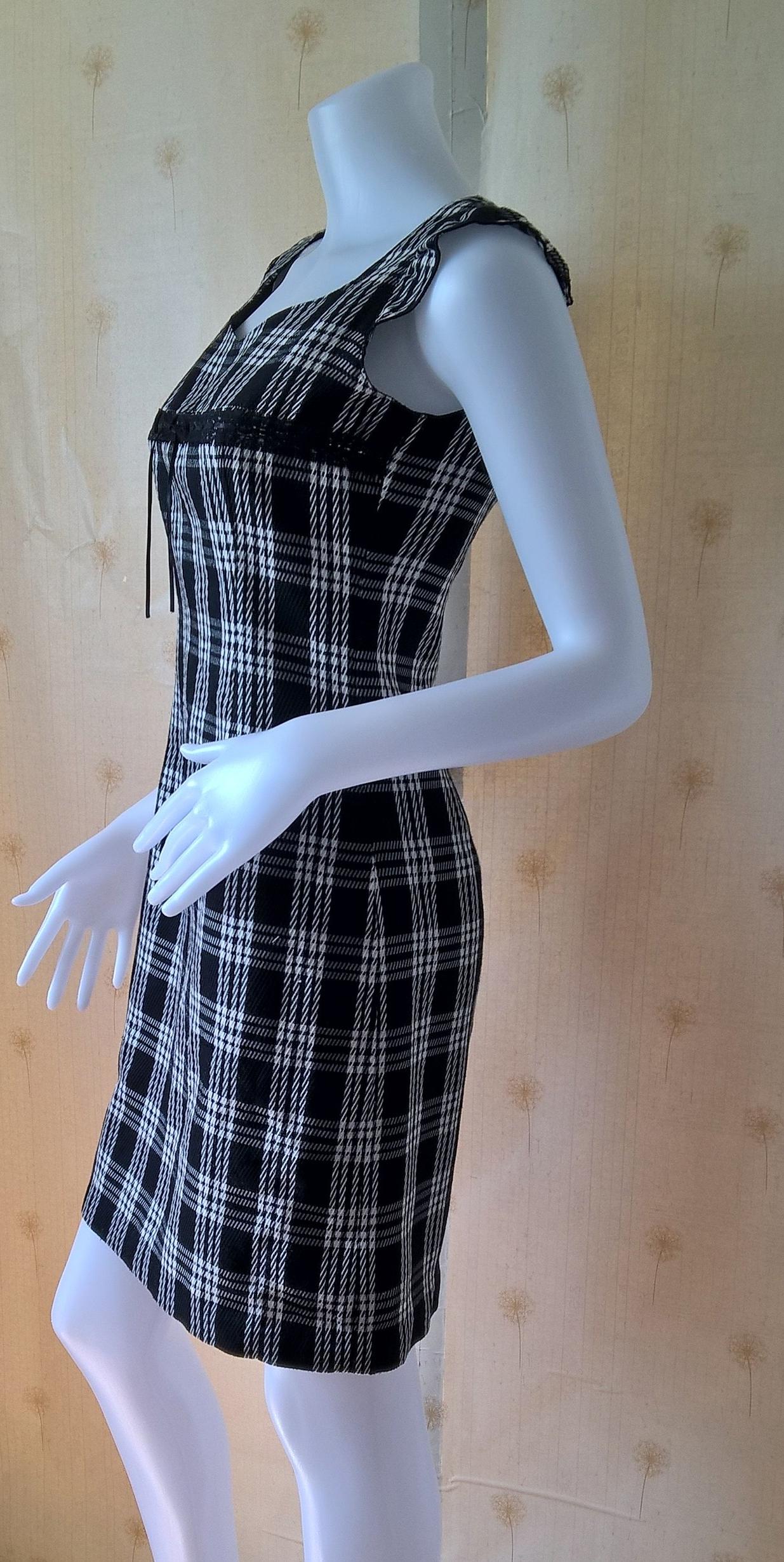 ชุดเดรส สีดำลายสก๊อต ผ้าทอ คอกว้าง แต่งรอบอกด้วยลูกไม้ดำ ผูกริบบิ้นดำเล็กตรงกลางหน้าอก มีซับในและติดซิปหลัง