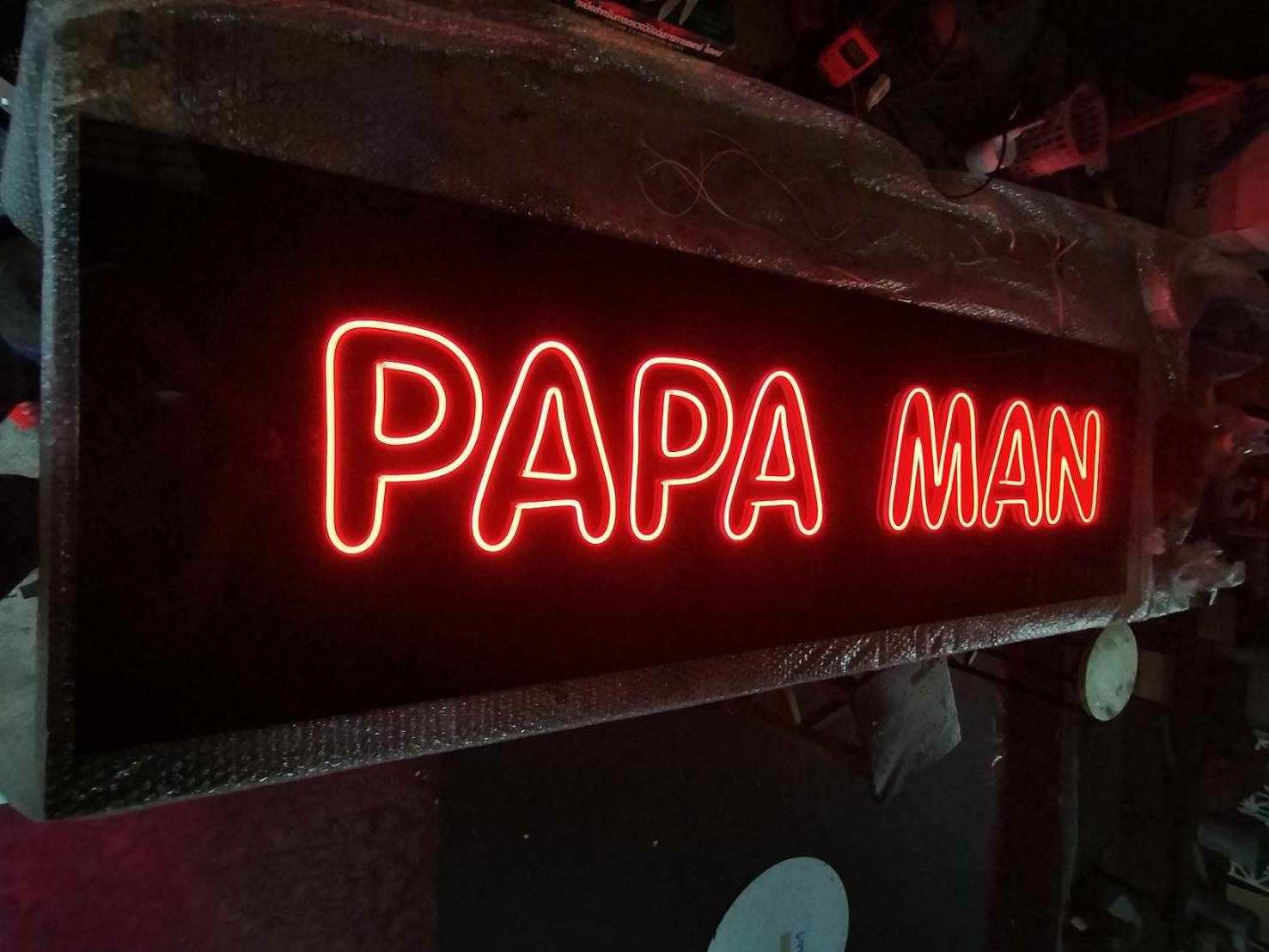 ป้ายไฟ LED ดัด - PAPA MAN วางบนอคลิคิกสีดำ