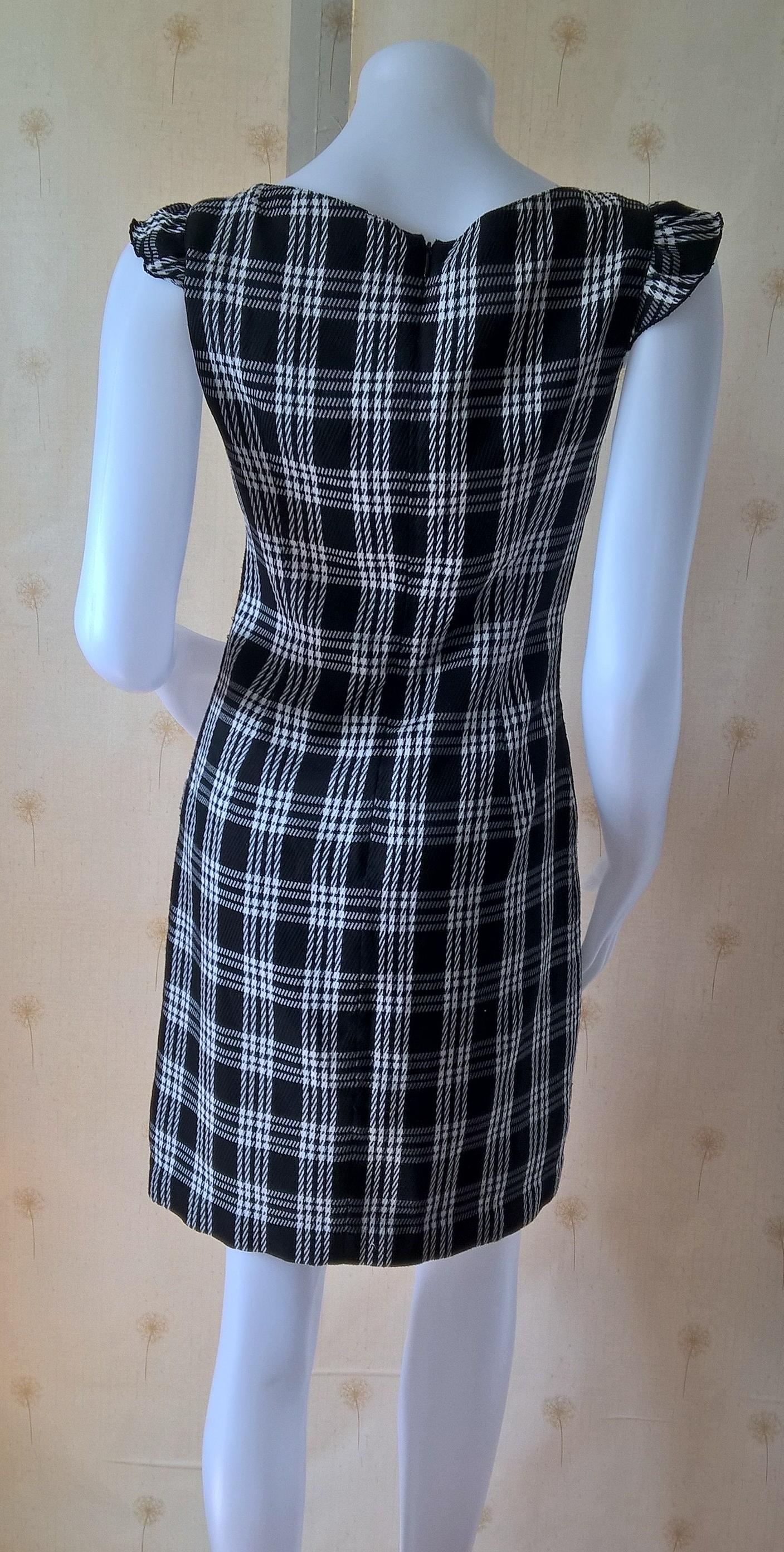 ชุดเดรส สีดำลายสก๊อต ผ้าทอ คอกว้าง แต่งรอบอกด้วยลูกไม้ดำ ผูกริบบิ้นดำเล็กตรงกลางหน้าอก มีซับในและติดซิปหลัง