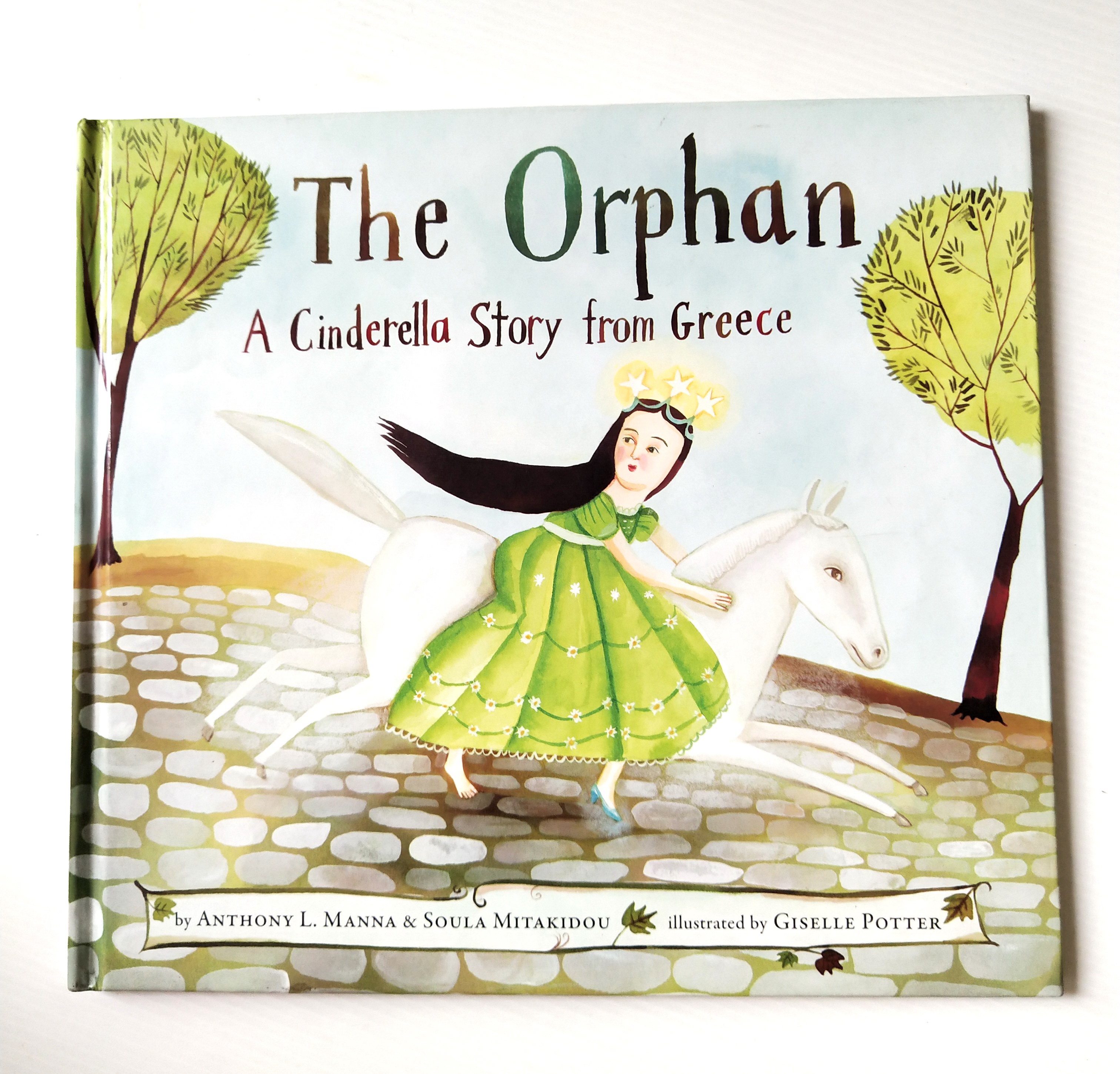 หนังสือนิทานเด็ก**มีตำหนิ ตามภาภาพ ฉบับภาษาอังกฤษ เรื่องราวของซินเดอเรลล่า แบบกรีก The Orphan ,A Cinderella Story from Greece โดย ANTHONY L. MANNA & SOULA MITAKIDOU ภาพโดย GISELLE POTTER,schwartz & wade books. new york