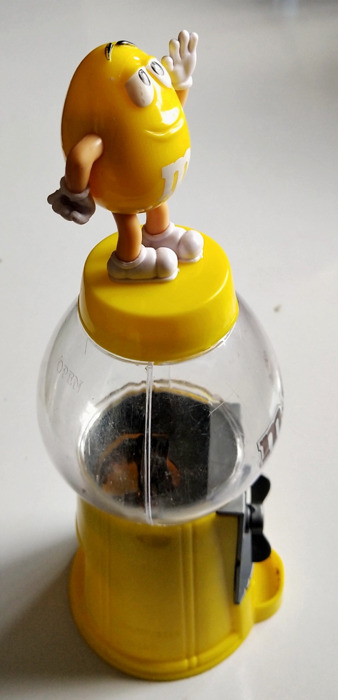 ของสะสม ตู้ไขขนมM&M ตัวสีเหลือง ยืนเท้าสะเอว และโบกมือ เปืดฝาใส่ขนม และไขขนมได้ปกติ