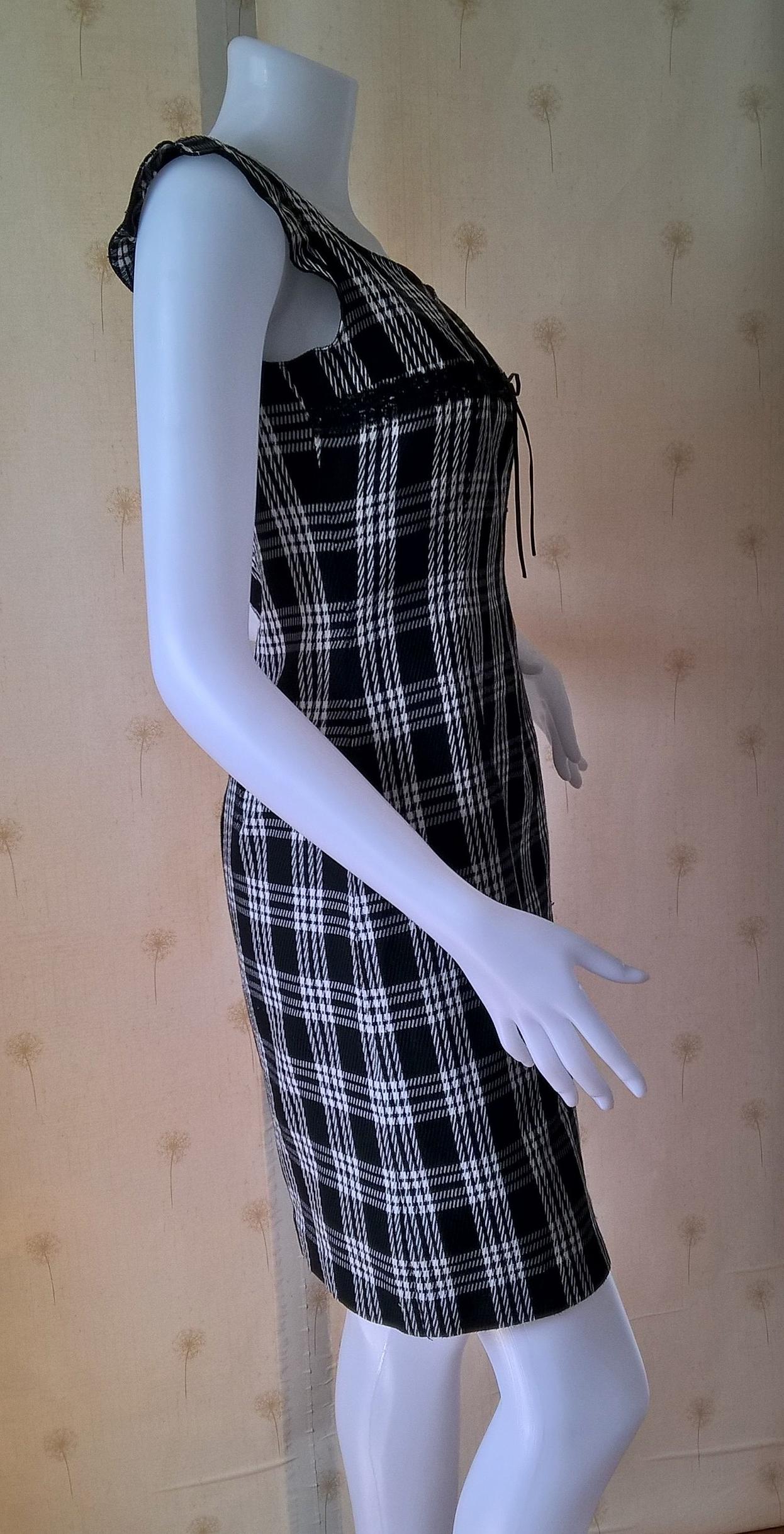 ชุดเดรส สีดำลายสก๊อต ผ้าทอ คอกว้าง แต่งรอบอกด้วยลูกไม้ดำ ผูกริบบิ้นดำเล็กตรงกลางหน้าอก มีซับในและติดซิปหลัง